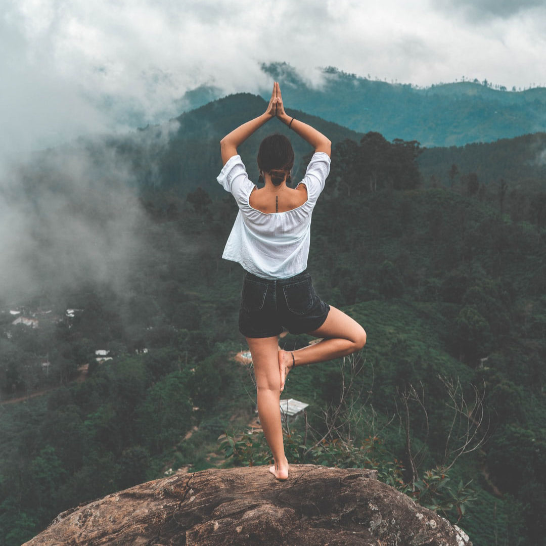 Girl in Tree Pose overlooking a mountain.